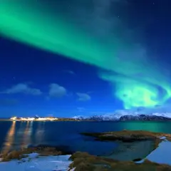 Zielona zorza polarna nad norweską wioską. Ciekawe ciekawostki o Norwegii: to zjawisko można podziwiać zimą.