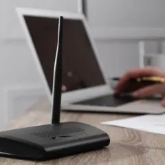 Router mit Antennen steht auf einem Holztisch. Ein Laptop hat kein WLAN mehr, der Nutzer versucht, das Problem zu lösen.