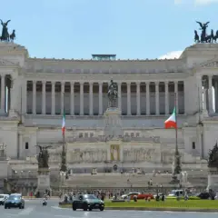 Monumentalny budynek na Piazza Venezia w Rzymie, z rzeźbami i flagami Włoch.