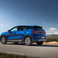 Un BYD Atto 3 azul en una carretera rural, listo para una prueba de manejo con montañas nevadas al fondo.