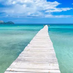 Holzsteg im türkisfarbenen Meer, Berge im Hintergrund. Perfekt für die mallorca beste reisezeit.