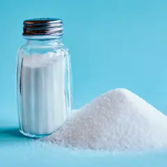 Saltkaret bredvid en hög med salt. Salt är en grundläggande ingrediens för att framhäva umami smak i matlagning.