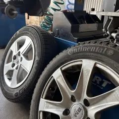 Dwa aluminiowe felgi z oponami Continental i Michelin, gotowe do prostowania felgi aluminiowej w warsztacie.