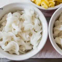 Biały makaron bez glutenu z ciecierzycy w miseczkach, obok żółtego makaronu.