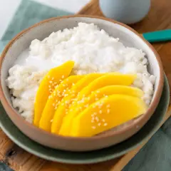 Ein Schälchen mit cremigem Klebreis und frischen Mangoscheiben, bestreut mit Sesam. Perfekt für ein Mango Sticky Rice Rezept.