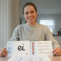 Lehrerin zeigt Grundschulkindern den Buchstaben S und das Alphabet.