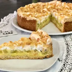 Ein köstlicher Rhabarberkuchen mit Pudding und Baiser, bestreut mit Mandelblättchen. Ein Stück Glück auf einem Teller.