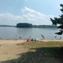 Słoneczny dzień nad jeziorem Przeczyckim. Ludzie kąpią się i odpoczywają na piaszczystej plaży.