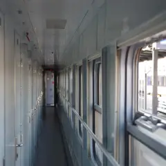 Korytarz wagonu sypialnego z rzędem drzwi po lewej i oknami po prawej.
