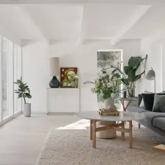 Ein helles, luftiges kleines Wohnzimmer skandinavisch einrichten mit grauem Sofa, Marmortisch und vielen Pflanzen.