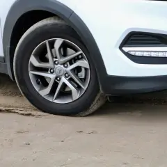 Koło samochodu na piasku, widoczny otwór centrujący w feldze.