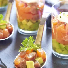 Délicieux tartare saumon fumé avocat servi en verrine et cuillère, garni de ciboulette.