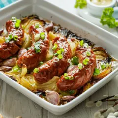 Pieczona biała kiełbasa z cebulą i czosnkiem, posypana szczypiorkiem. Proste i pyszne przepisy na dania z kiełbasą.