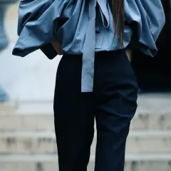 Eleganckie stylizacje z czarnymi spodniami. Kobieca sylwetka w szarej, bufiastej bluzce i dopasowanych czarnych spodniach.