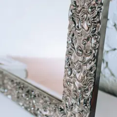 Eleganckie lustro do sypialni glamour z bogato zdobioną, srebrną ramą.