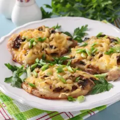 Schab w plastrach pieczony w piekarniku z pieczarkami i serem, posypany szczypiorkiem.