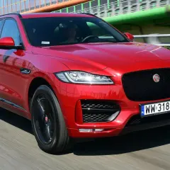 Czerwony Jaguar F-Pace na drodze. Kierowca w środku. Wiele pozytywnych jaguar f pace opinie potwierdza jego styl.