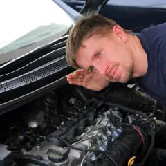 Mechanik nasłuchuje pracy silnika, skupiając się na kolektorze.