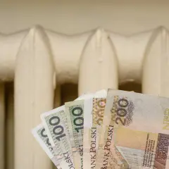 Pieniądze w ręku na tle grzejnika. Czy to zapowiedź bonu energetycznego 2026?