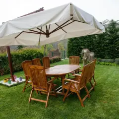 Drewniany zestaw mebli ogrodowych pod parasolem. Idealne, jakie drewno na meble ogrodowe, by cieszyć się latem.