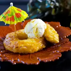 Friterad banan serverad med vaniljglass och en liten gul parasoll. En läcker dessert som påminner om soliga dagar.
