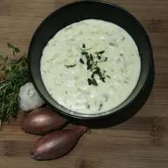 Kremowy, biały sos do pizzy z ziołami, czosnkiem i szalotką na drewnianej desce. Idealny dodatek do każdej pizzy.