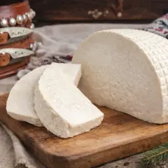 Bundz co to? Biały, świeży ser z owczego mleka, pokrojony na desce, z orzechami i ozdobnym pasem w tle.