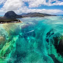 Podwodny wodospad na Mauritiusie, marzenie o wizie do raju. Turkusowa woda, góry i łódź.