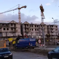 Budowa bloków mieszkalnych w Gdańsku. W tle dźwigi budowlane, na pierwszym planie samochody i maszyny budowlane. Ceny mieszkań gdańsk mogą być wysokie.