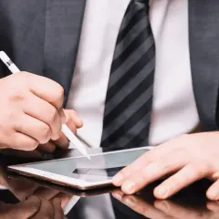 Hombre con traje firma un contrato con certificado digital en una tablet.