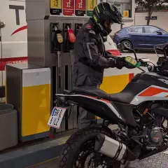 Motociclista repostando su moto 390 Adventure. La pregunta sobre qué gasolina usan las motos de 49cc es relevante para este tipo de vehículos.