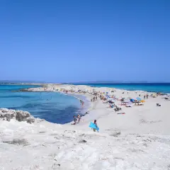 Gente disfrutando de un día soleado en las **playas blancas** con aguas turquesas y cielo azul.