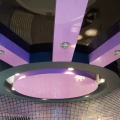 Nowoczesny sufit napinany w kolorach fioletu i granatu, z okrągłym elementem centralnym i wbudowanymi punktami świetlnymi.