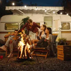 Amigos disfrutan de una fogata y malvaviscos junto a su caravana, una noche perfecta para aprender como acampar.