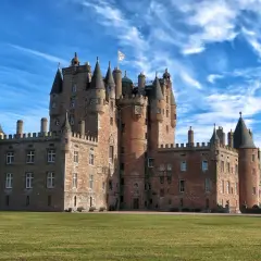Castillo escocés con torres cónicas y un gran césped verde, perfecto para tus viajes a Escocia.