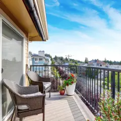 Uroczy balkon z wygodnymi meblami i kwitnącymi kwiatami. Jasne kafle na balkon tworzą przytulną atmosferę.