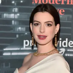 Anne Hathaway, której wiek jest często przedmiotem dyskusji, prezentuje się olśniewająco w złotej biżuterii na tle logo Amazon Prime Video.