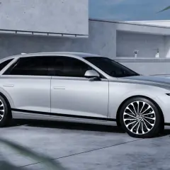 Srebrny Hyundai Grandeur z czarnymi akcentami i felgami stoi przed nowoczesnym budynkiem.