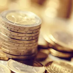 Pile de pièces en euros, certaines gravées de la marque APC, symbolisant la richesse et l'épargne.