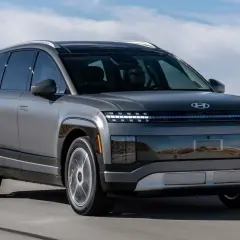 Szary Hyundai Ioniq 9 jedzie po pustynnej drodze. Futurystyczny design z charakterystycznymi światłami.