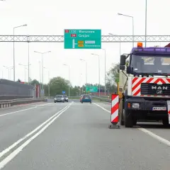 Ciężarówka MAN blokuje drogę, ostrzegając przed wyprzedzaniem na podwójnej ciągłej. Mandat za takie wykroczenie jest wysoki.