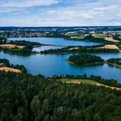 Malownicze jeziora i lasy, gdzie są Kaszuby. Widok z lotu ptaka na zielone wzgórza, pola i zabudowania.