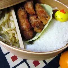 A delicious karaage bento box with crispy fried chicken, fluffy rice, pickled cabbage, and a cute chick-shaped decoration.