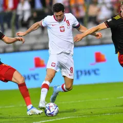 Piłkarz Polski z numerem 9 walczy o piłkę z dwoma zawodnikami Belgii. Emocjonujący mecz Polska-Belgia.