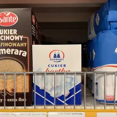 Półka sklepowa z różnymi rodzajami cukru: trzcinowym, białym w kostkach i w kryształkach.