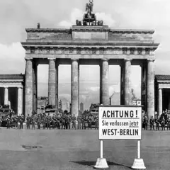 Brandenburger Tor, Soldaten und Panzer stehen Spalier. Ein Schild warnt: "ACHTUNG! Sie verlassen jetzt WEST-BERLIN". Ein Symbol des kalten Krieges.