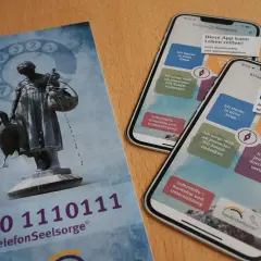 Flyer und Smartphones mit der App "Krisen Kompass" zeigen Wege zur rettung aus der not. Die Telefonseelsorge bietet Hilfe.