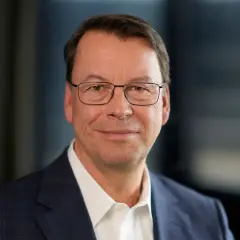 Porträt eines Mannes mit Brille im Anzug. Er könnte ein wichtiger Manager sein, der die Entwicklung der SUSS Microtec Aktie beeinflusst.