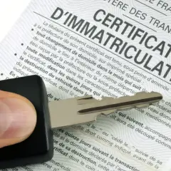 Clé de voiture sur un certificat d'immatriculation, symbolisant les documents d'achat d'une voiture d'occasion.