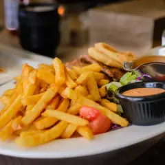 Chrupiące frytki z piekarnika, idealne na lekki posiłek. Zastanawiasz się nad ich kcal? Podane z sosem i sałatką.